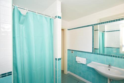 a bathroom with a blue shower curtain and a sink at Charme Hotel La Villa Tina in Ischia