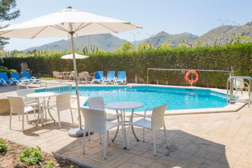 uma piscina com mesas e cadeiras e um guarda-sol em Apartamentos Massol em Port de Pollença