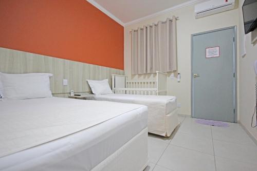 奧林匹亞的住宿－Glória Hotel，一间卧室设有两张床和橙色的墙壁