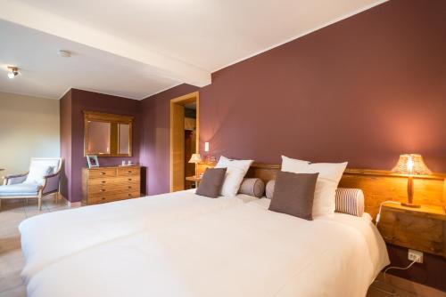 a bedroom with a large white bed and a brown wall at A la ferme du Pere Eugene in Malmedy