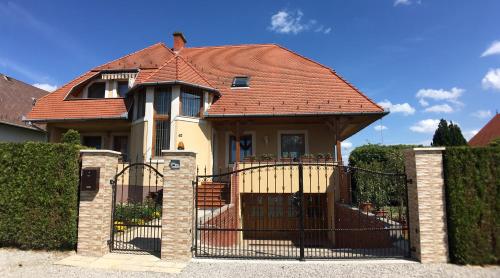 a house with a gate with a red roof at Hevizquelle Apartments in Hévíz