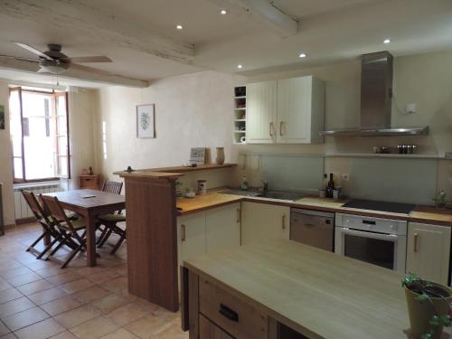 a kitchen with white cabinets and a table and chairs at Le logis de la Fontaine in Ceyreste