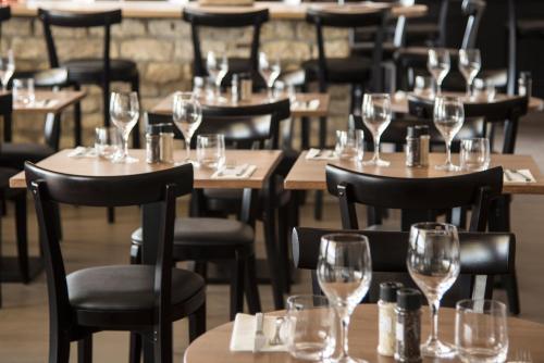 un restaurant avec des tables et des chaises vides et des verres à vin dans l'établissement Les Bains Boyardville - Hôtel et Restaurant, à Boyardville