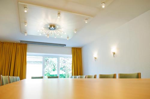 a dining room with a large table and a chandelier at Hotel Petersen in Bad Zwischenahn