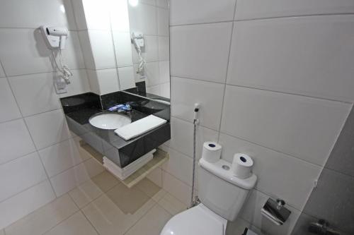 a bathroom with a white toilet and a sink at Glória Hotel in Olímpia