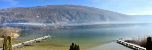 a view of a lake with a dock and a mountain at Novalaise Plage in Novalaise