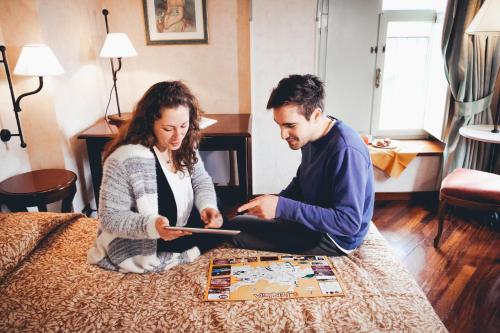 a man and woman sitting on a bed playing a board game at Hotel Fortuna in Perugia