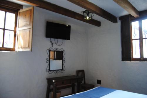 a bedroom with a bed and a tv on the wall at Hotel Casa Índigo in San Cristóbal de Las Casas