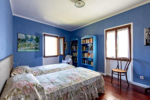 a blue bedroom with two beds and a book shelf at La Baita in Gardone Riviera