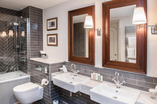 a bathroom with two sinks and a toilet and a mirror at De Vere Tortworth Court in Wotton-under-Edge