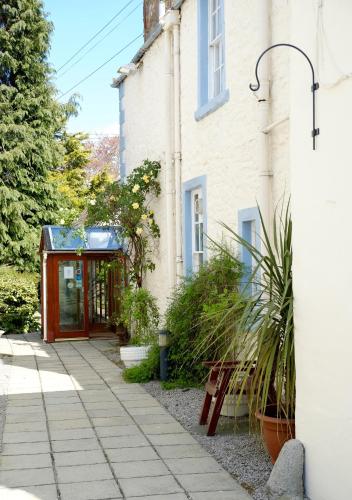 a building with a red door next to a sidewalk at Selkirk Arms Hotel in Kirkcudbright