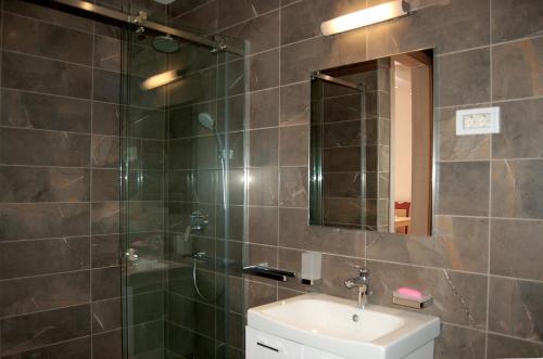 a bathroom with a shower and a sink and a mirror at Vasiliki Seaside Apartments in Petrovac na Moru