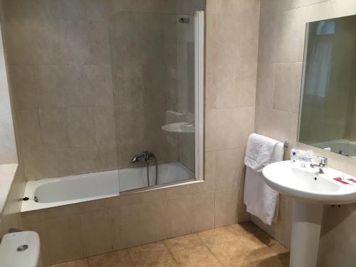 a bathroom with a tub and a sink and a shower at Hotel Errekagain in Aracaldo