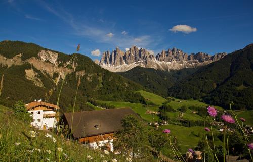 a mountain range with a building in a green field at Putzerhof in Funes