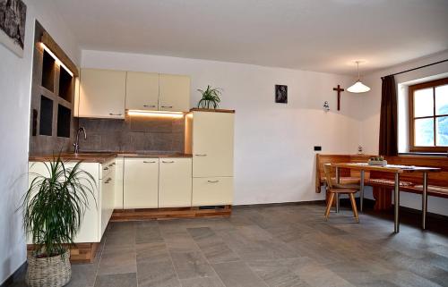 a kitchen with white cabinets and a table with a potted plant at Putzerhof in Funes