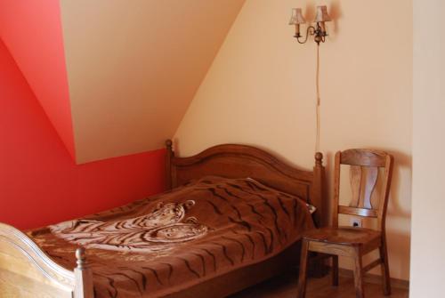 a bedroom with a bed and a chair at Malinowy Domek in Młyńczyska