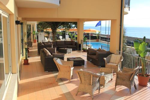 a patio with couches and chairs and the ocean at Lion's Hotel in Falerna