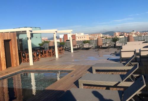 a deck with chairs and a pool on a roof at Hotel Urpí in Sabadell
