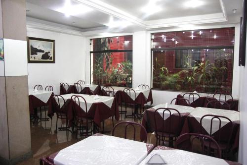 un comedor con mesas, sillas y ventanas en Free Palace Hotel, en São Paulo