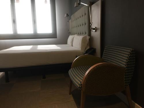 a bedroom with a bed and a chair and a window at Hotel Urpí in Sabadell