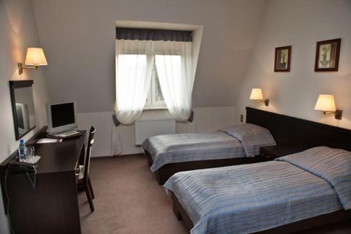 a hotel room with two beds and a desk with a laptop at Portius in Krosno