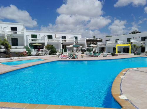 プエルト・デル・カルメンにあるApartamento Renovado,vistas piscina, aire acondicionado,wifiの白い建物の前の大きなスイミングプール