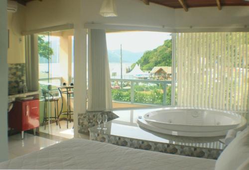 a large bath tub in a room with a large window at Pousada Ilha da Magia in Florianópolis