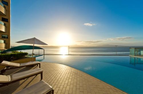 a swimming pool with a view of the ocean at Majestic Palace Hotel in Florianópolis