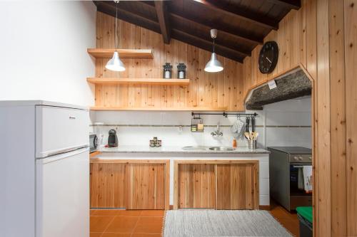 a kitchen with wooden cabinets and a white refrigerator at Retiro do Tico in Porto Formoso