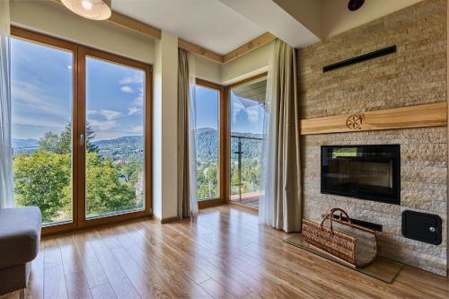 a living room with a fireplace and large windows at Smrekowa Polana Resort & Spa in Zakopane