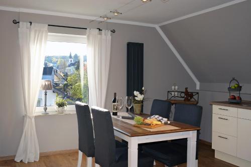 a dining room table with chairs and a window at Ferienwohnung Maarland in Schalkenmehren