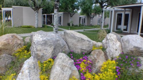 a rock retaining wall with flowers in a yard at Villaggio Turistico Lugana Marina in Sirmione