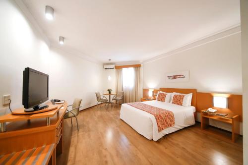 a hotel room with a bed and a flat screen tv at Grand Hotel Royal Sorocaba by Atlantica in Sorocaba