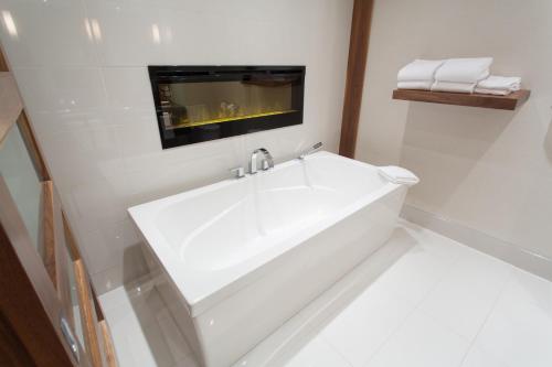 a white sink in a white bathroom with towels at Atlantic Host Hotel, Trademark Collection by Wyndham in Bathurst
