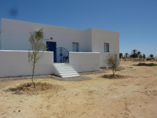 a white building in the desert with trees in front of it at Dar Chick Yahia Ile De Djerba in Mezrane