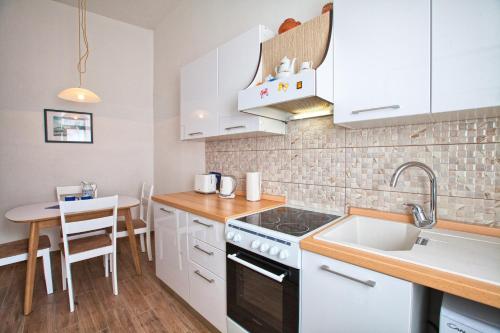 a kitchen with white cabinets and a sink and a table at Apartment Rosy in Pula