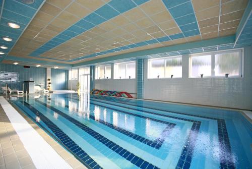 a large swimming pool with blue tiles on the ceiling at Hotel Ambra in Luhačovice