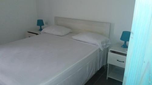 a small bedroom with a white bed and two lamps at Residencial Las Estrellas in Boca Chica