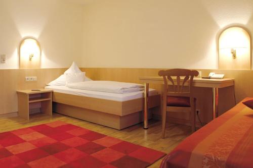 a bedroom with a bed and a desk and a chair at Hotel Landgasthof Grüner Baum in Hochdorf