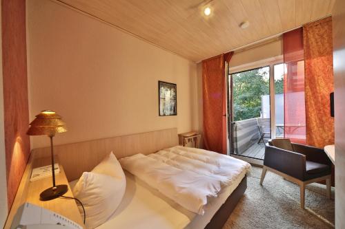 Schlafzimmer mit einem Bett, einem Tisch und einem Fenster in der Unterkunft Landidyll Wilminks Parkhotel in Neuenkirchen