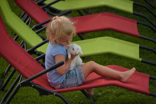 a little girl sitting on a red chair holding a stuffed animal at Feriengut Linortner in St. Wolfgang