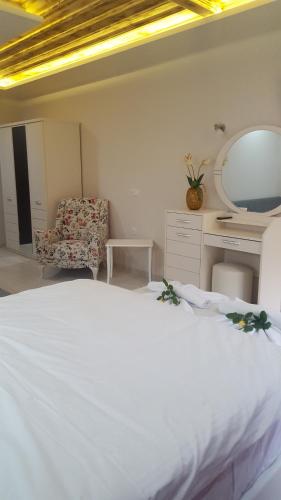 a bedroom with a white bed and a chair at Archontiko Liamas in Stavros