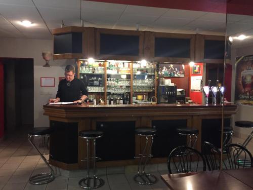 a man standing at a bar in a restaurant at Hôtel Le Bambi in Baume-les-Dames