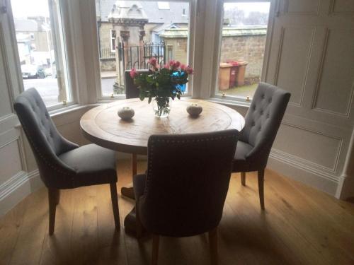 una mesa de comedor con sillas y un jarrón de flores en Carbet Lodge en Dundee