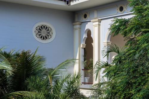 a white house with a window and palm trees at Hotel del Parque in Guayaquil