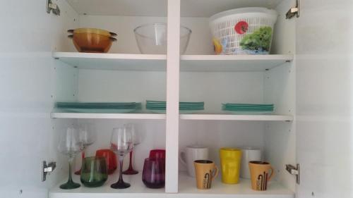 un meuble de cuisine rempli de vaisselle et de verres à vin dans l'établissement Studio Lora G 031, à Saint-Louis