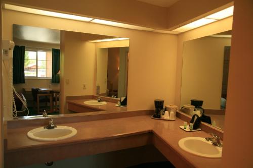 a bathroom with two sinks and two mirrors at Black Canyon Motel in Montrose