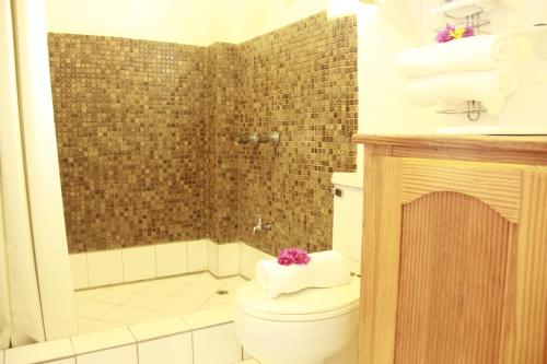 a bathroom with a toilet and a shower with towels at Gem Holiday Beach Resort in Saint Georgeʼs