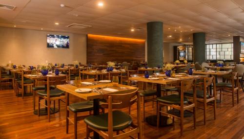 una sala da pranzo con tavoli e sedie in legno di Hotel Luzeiros Recife a Recife