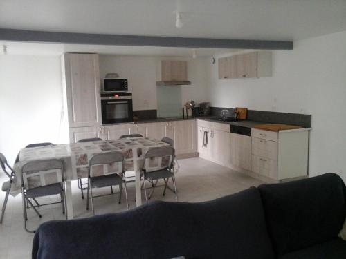 une cuisine avec une table et des chaises dans une pièce dans l'établissement Maison au calme, à Vezins